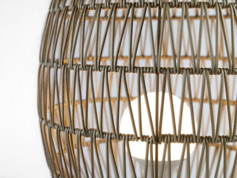 May include: A close-up of a woven wicker pendant light fixture with a white light bulb inside.