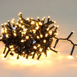 Könnte beinhalten: Eine Lichterkette mit warmweißen LED-Weihnachtslichtern und schwarzem Kabel. Die Lichter sind aufgerollt und bereit zum Aufhängen.