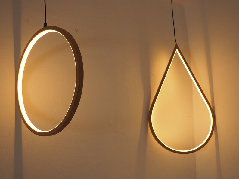 May include: Two modern light fixtures hanging from the ceiling. One is a circular ring and the other is a teardrop shape.