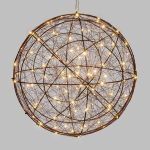 Może przedstawiać: Duża, okrągła kula z drutu z ciepłymi białymi diodami LED. Kula wykonana jest z cienkich, splecionych ze sobą drutów i ma rustykalne, metaliczne wykończenie.