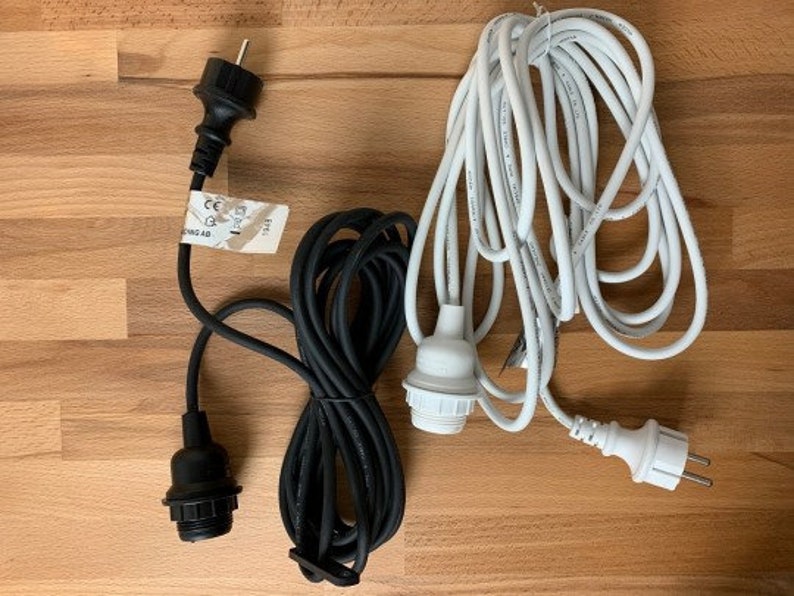 May include: Two electrical cords with black and white plugs and cords. The black cord has a label that reads "CE" and "220-240V~ 50Hz 100W".