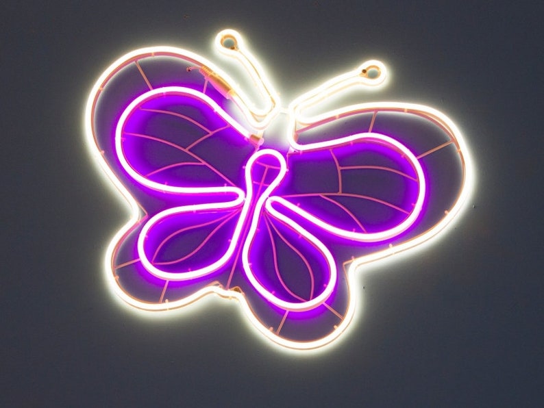 May include: A white neon butterfly with a purple outline. The butterfly is a popular design for home decor and can be used to add a touch of whimsy to any room.