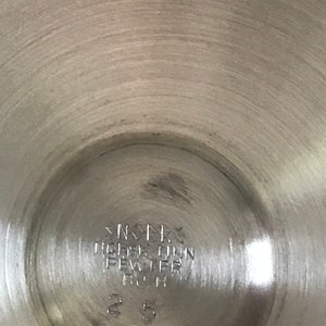 Puede incluir: Primer plano de la parte inferior de una jarra de plata con la inscripci&oacute;n "NORSK TINN PEWTER FIN 25"