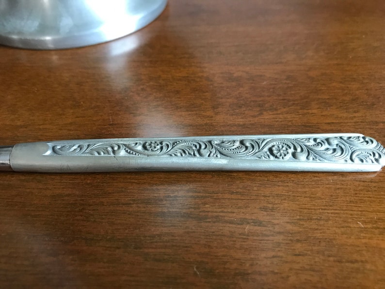 Puede incluir: Un cuchillo de plata con un dise&ntilde;o floral adornado grabado en el mango.