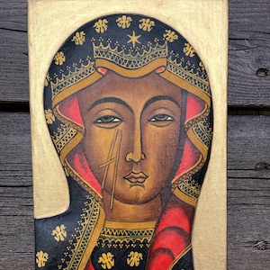 May include: A hand-painted icon of the Virgin Mary with a gold background and black and gold patterned robe. The icon is framed in a gold frame.