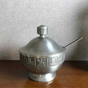 Puede incluir: Un azucarero de plata con tapa y una cucharita. El bol est&aacute; decorado con un dise&ntilde;o en relieve de barcos y caballos.