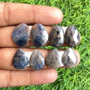 Puede incluir: Seis piedras preciosas de zafiro azul facetadas en forma de pera, presentadas sobre un fondo blanco.
