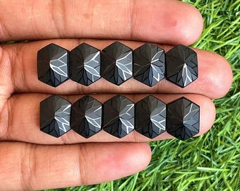 May include: Eight black faceted gemstone cabochons, each with a hexagonal shape and a pointed top. The gemstones are arranged in two rows of four, with the points of the gemstones facing upwards.