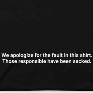 Può includere: T-shirt nero con testo bianco. Il testo recita: "Ci scusiamo per il difetto di questa maglietta. I responsabili sono stati licenziati."