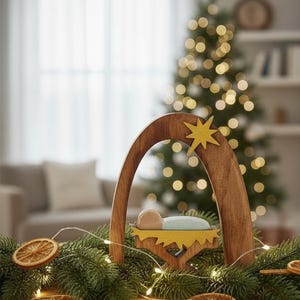 Op de afbeelding: Houten kerststal met een gele ster en een baby in een kribbe. De sc&egrave;ne is omgeven door groen, gedroogde sinaasappelschijfjes en fee&euml;rieke lichtjes. Op de achtergrond staat een kerstboom met vage lichtjes.