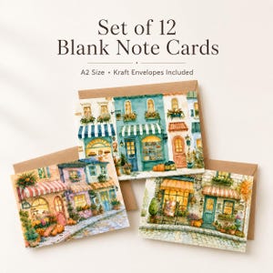 May include: A set of 12 blank note cards with A2 size and kraft envelopes included. The cards feature watercolor illustrations of European-style storefronts with striped awnings, flower boxes, and cobblestone streets in warm, inviting colors.