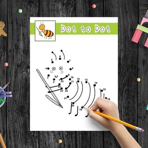 Op de afbeelding: Een zwart-witte verbind-de-stippen-activiteitspagina met de woorden "Dot to Dot" bovenaan. Een kinderhand tekent een lijn die de stippen verbindt met een geel potlood.