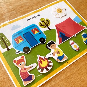 Puede incluir: Una ilustraci&oacute;n colorida de una escena de camping con una caravana azul, una tienda de campa&ntilde;a roja, una fogata, dos personas y un sol. El texto "Camping Day" est&aacute; en la parte superior de la imagen.