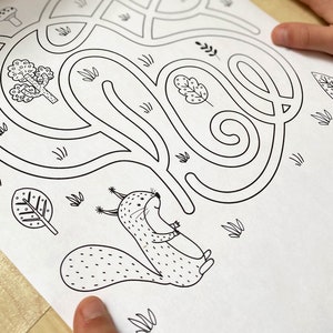 May include: A black and white maze with a squirrel at the bottom. The maze is shaped like a winding path through a forest with trees and leaves.