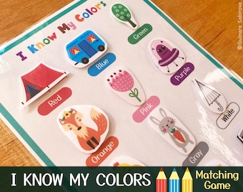 May include: A colorful educational game for kids to learn colors. The game features a variety of images, including a tent, a camper van, a flower, a UFO, an umbrella, a fox, a rabbit, and a tree. The game is titled "I Know My Colors" and includes the text "Matching Game".