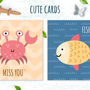 May include: Two greeting cards featuring cute animal illustrations. The first card shows a pink crab on a yellow and orange background with the text "Miss You". The second card shows a yellow fish on a blue background with the text "FISHY".