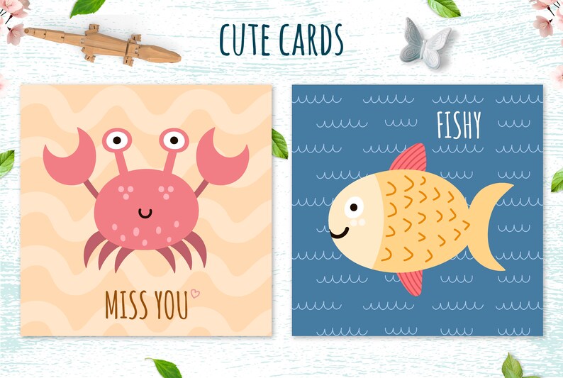 May include: Two greeting cards featuring cute animal illustrations. The first card shows a pink crab on a yellow and orange background with the text "Miss You". The second card shows a yellow fish on a blue background with the text "FISHY".