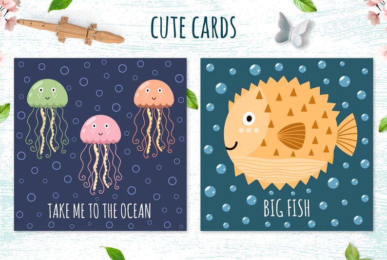May include: Two illustrated cards with a nautical theme. The first card features three jellyfish in shades of green, pink, and orange against a dark blue background with white bubbles. The text on the card reads "Take me to the ocean". The second card features a yellow pufferfish with brown spots and a brown tail fin against a dark blue background with white bubbles. The text on the card reads "Big Fish".