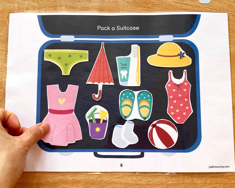 Puede incluir: Una maleta azul con una variedad de art&iacute;culos en su interior, incluyendo un vestido rosa, un traje de ba&ntilde;o, un sombrero, un paraguas, sandalias, calcetines, una pelota de playa, un cubo y un cepillo de dientes. El texto "Pack a Suitcase" est&aacute; en la parte superior de la imagen.