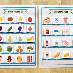 May include: Two colorful charts with the word "Supermarket" at the top. The charts are divided into squares, each containing a different image of a food item. The left chart features fruits, vegetables, and other grocery items. The right chart features packaged food items, such as pasta, salt, and eggs.