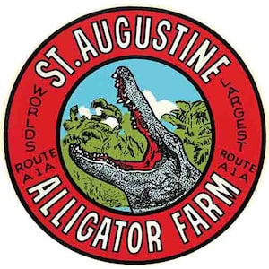 May include: A red and white circular sign with the text "St. Augustine's Largest Alligator Farm" and a cartoon image of an alligator with its mouth open. The text "Route A1A" appears twice on the sign.