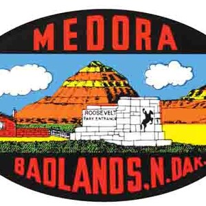 May include: A vintage oval-shaped sticker with a black background and red text that reads "Medora Badlands N. Dak." The sticker features a colorful illustration of a landscape with a red and yellow butte, a white building with the text "Roosevelt Park Entrance", and a blue sky with white clouds.