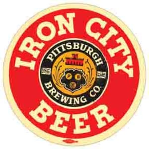 Könnte beinhalten: Ein rundes Schild in Rot und Weiß mit dem Text "Iron City Beer" in einem weißen Kreis um einen schwarzen Kreis mit dem Text "Pittsburgh Brewing Co." und einem Logo in der Mitte.