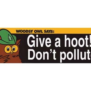 May include: A yellow and black sign featuring a cartoon owl wearing a green hat. The sign reads "Woodsy Owl Says: Give a hoot! Don't pollute."