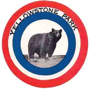 May include: A vintage, circular Yellowstone National Park patch with a red outer ring, a white inner ring, and a blue ring in the middle. A black bear is standing on a gray background in the center of the patch. The text "Yellowstone Park" is written in a white circle around the bear.