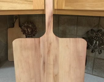 May include: A wooden pizza peel with a long handle and a rounded rectangular blade. The peel is made of light wood and has a natural finish.