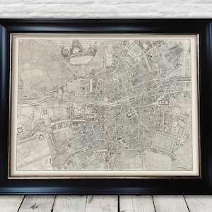 May include: A black and white antique map of Dublin, Ireland, framed in a black frame. The map shows the city's streets, buildings, and landmarks. The map is dated 1750.