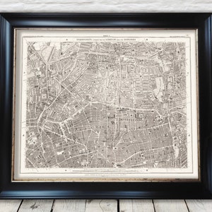 May include: A vintage black and white map of London and its suburbs, printed on paper and framed in a black frame. The map is titled "Stanford's  Correct Map of London and its Suburbs".