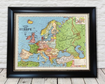 Op de afbeelding: Een vintage kaart van Europa met landsgrenzen en namen. De kaart is gedrukt op papier en ingelijst in een zwart frame. De kaart is getiteld "Bacon's Standard Map of Europe".