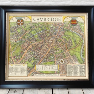Op de afbeelding: Een vintage kaart van Cambridge, Engeland, met een gedetailleerde illustratie van de colleges, kerken, parken en andere bezienswaardigheden van de stad. De kaart is ingelijst in een zwart frame en heeft een gouden rand.