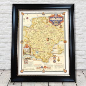 Może przedstawiać: Antyczna mapa hrabstwa Devon w Anglii, w czarnej ramie. Mapa jest żółta z czerwonymi i niebieskimi akcentami. Tytuł "Devonshire" znajduje się na czerwonej wstędze u góry mapy. Mapa jest otoczona ozdobną ramką z herbami.