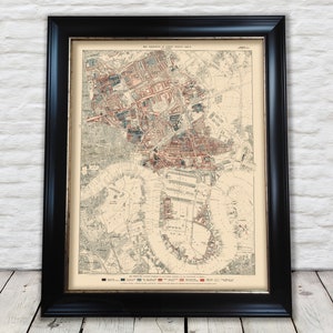 May include: An antique map of London, England, printed in black, red, and blue ink. The map shows the city's streets, buildings, and parks. The map is framed in a black frame.