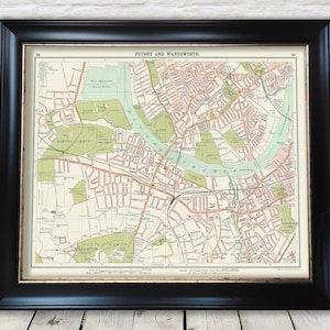 Op de afbeelding: Ingelijste vintage kaart van Putney en Wandsworth, met gedetailleerde straten, groene parken en de rivier de Theems. Gepresenteerd in een zwart frame, ideaal voor woondecoratie.