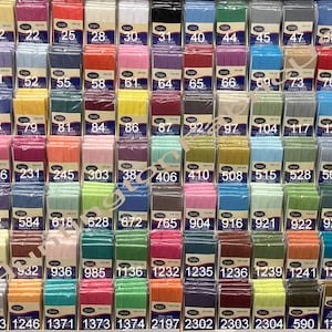 May include: A wall display of 50 different colors of double-fold bias tape, each color is labeled with a number. The tape is packaged in clear plastic.