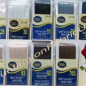 May include: A display of various colors of Wrights Soft & Easy Hem Tape. The tape is packaged in clear plastic with a blue and gold label. The label includes the product name, brand, and product number. The tape is available in a variety of widths and colors, including white, black, brown, and blue.