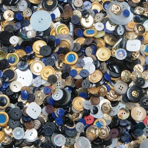 May include: A large collection of assorted buttons in various colors, shapes, and sizes. The buttons are made of different materials, including plastic, metal, and wood. Some buttons have a shiny finish, while others have a matte finish.