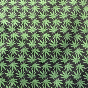 May include: A black fabric with a repeating pattern of green marijuana leaves.