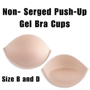 May include: Two beige gel bra cups with the text "Non-Serged Push-Up Gel Bra Cups" and "Size B and D". The cups are a light, neutral color and have a smooth texture. They are designed to provide push-up support.