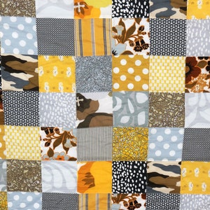 May include: A patchwork quilt with a variety of yellow, brown, gray, and white patterns. The quilt is made up of squares of different fabrics, each with a unique design.