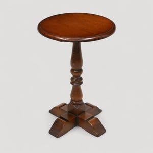 May include: A small, round, wooden side table with a dark brown finish. The table has a pedestal base and a four-legged base. The tabletop is approximately 46 cm in diameter. The table is suitable for a living room or bedroom.