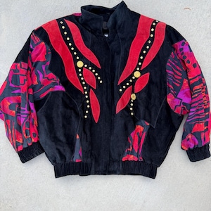 May include: Black vintage jacket with red and pink accents. The jacket features red suede-like panels with gold-colored button details and patterned sleeves. The jacket has a high collar and a fitted waist.