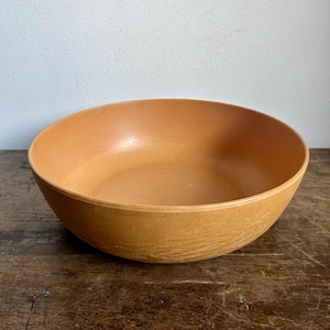 Pode incluir: Uma tigela grande, redonda e de madeira com um acabamento castanho natural. A tigela é feita de madeira e tem uma superfície lisa e polida.