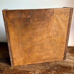 May include: A wooden box with a light brown finish. The box has a simple design with no visible hardware or embellishments.