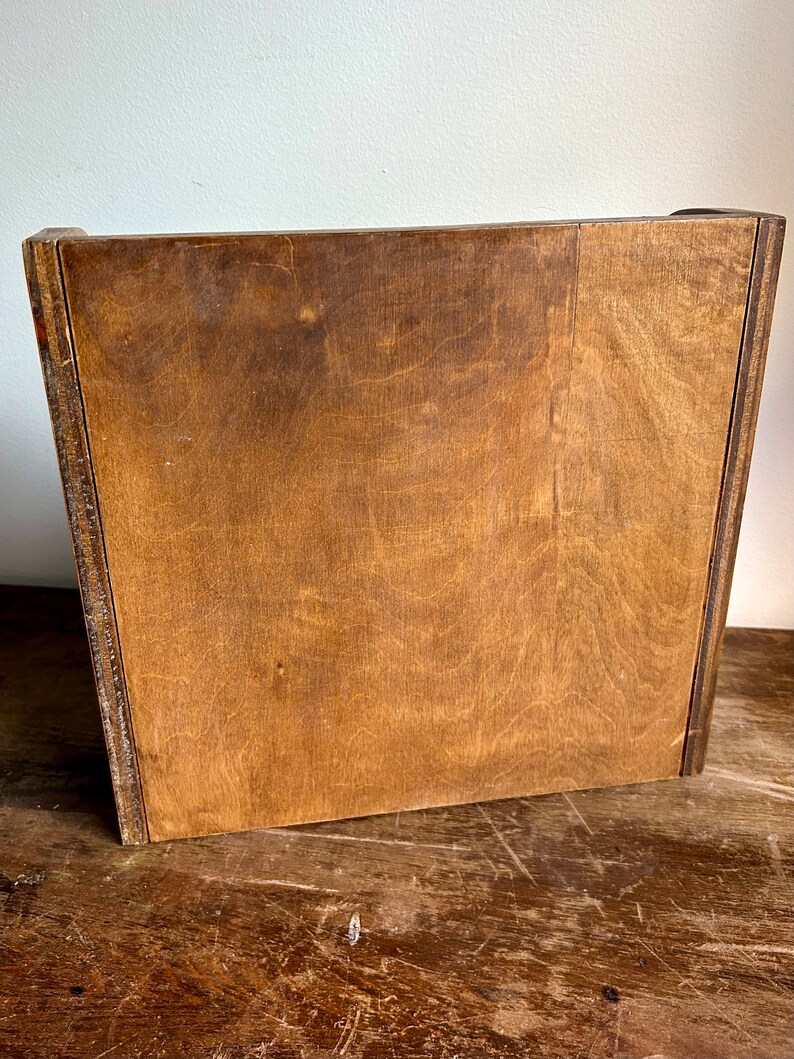 May include: A wooden box with a light brown finish. The box has a simple design with no visible hardware or embellishments.