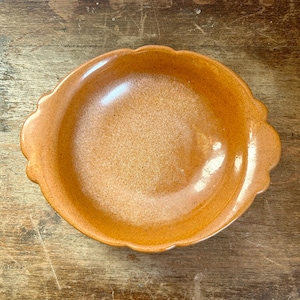 May include: A brown ceramic bowl with a scalloped edge. The bowl has a glossy finish and is empty.