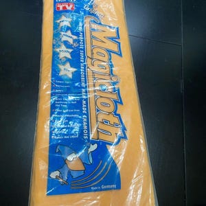 Peut inclure: Un chiffon de nettoyage orange rectangulaire emballé dans une pochette en plastique transparent. L'étiquette bleue porte le texte Magicloth, The Original, Multi-Purpose Super Absorbent Man-Made Chamois et Made in Germany, avec un magicien.